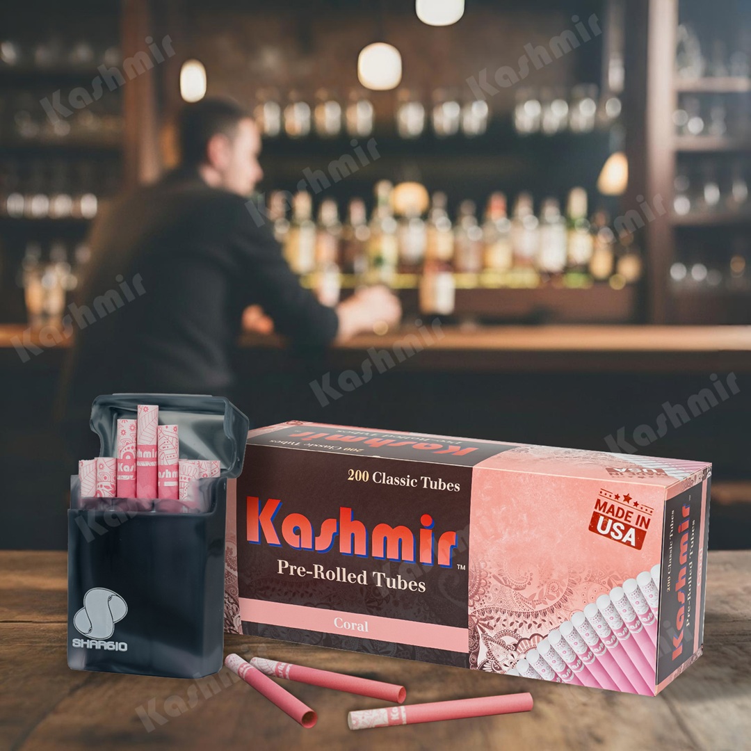 Kashmir Coral pre-rolled tubes, 200-count carton with an open pocket case of pink tubes on a bar counter; Made in USA badge visible.