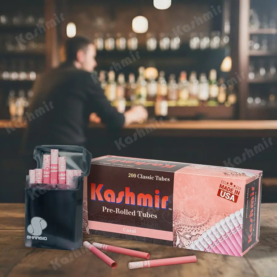 Kashmir Coral pre-rolled tubes, 200-count carton with an open pocket case of pink tubes on a bar counter; Made in USA badge visible.