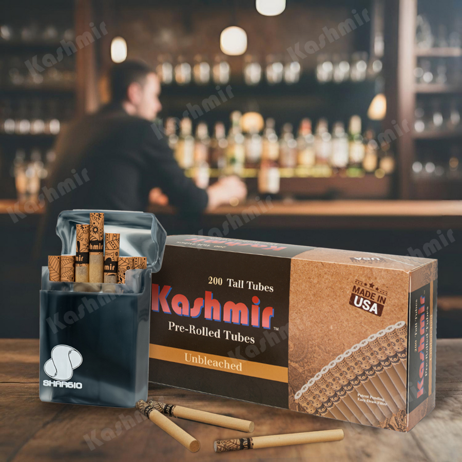 Carton of Kashmir Unbleached Tall pre-rolled cigarette tubes (200 count, Made in USA) on a bar with a translucent pocket case full of natural tan tubes and a few loose tubes in front.